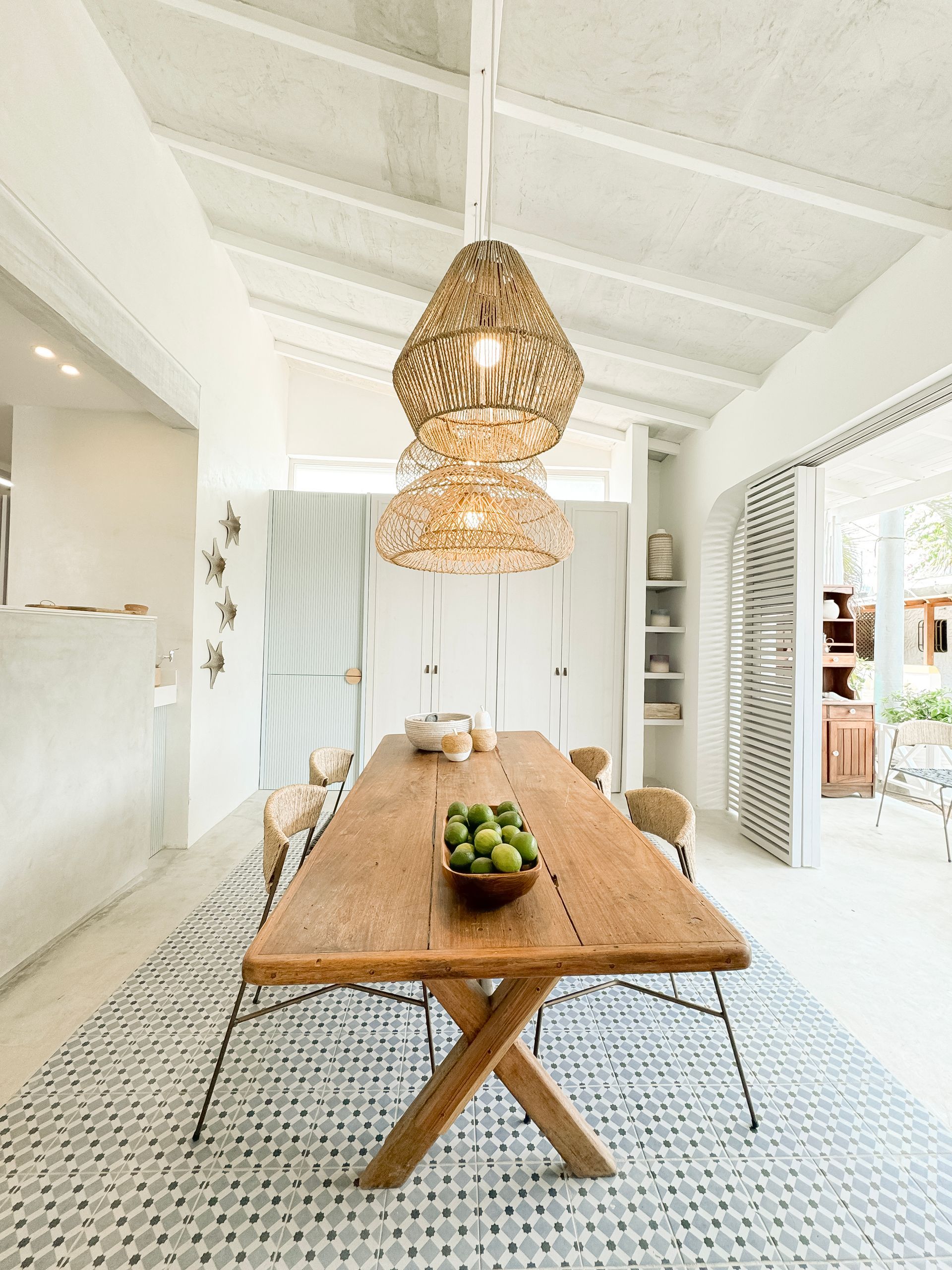 Comedor con mesa de madera, sillas y candelabro, decorado con manzanas verdes.