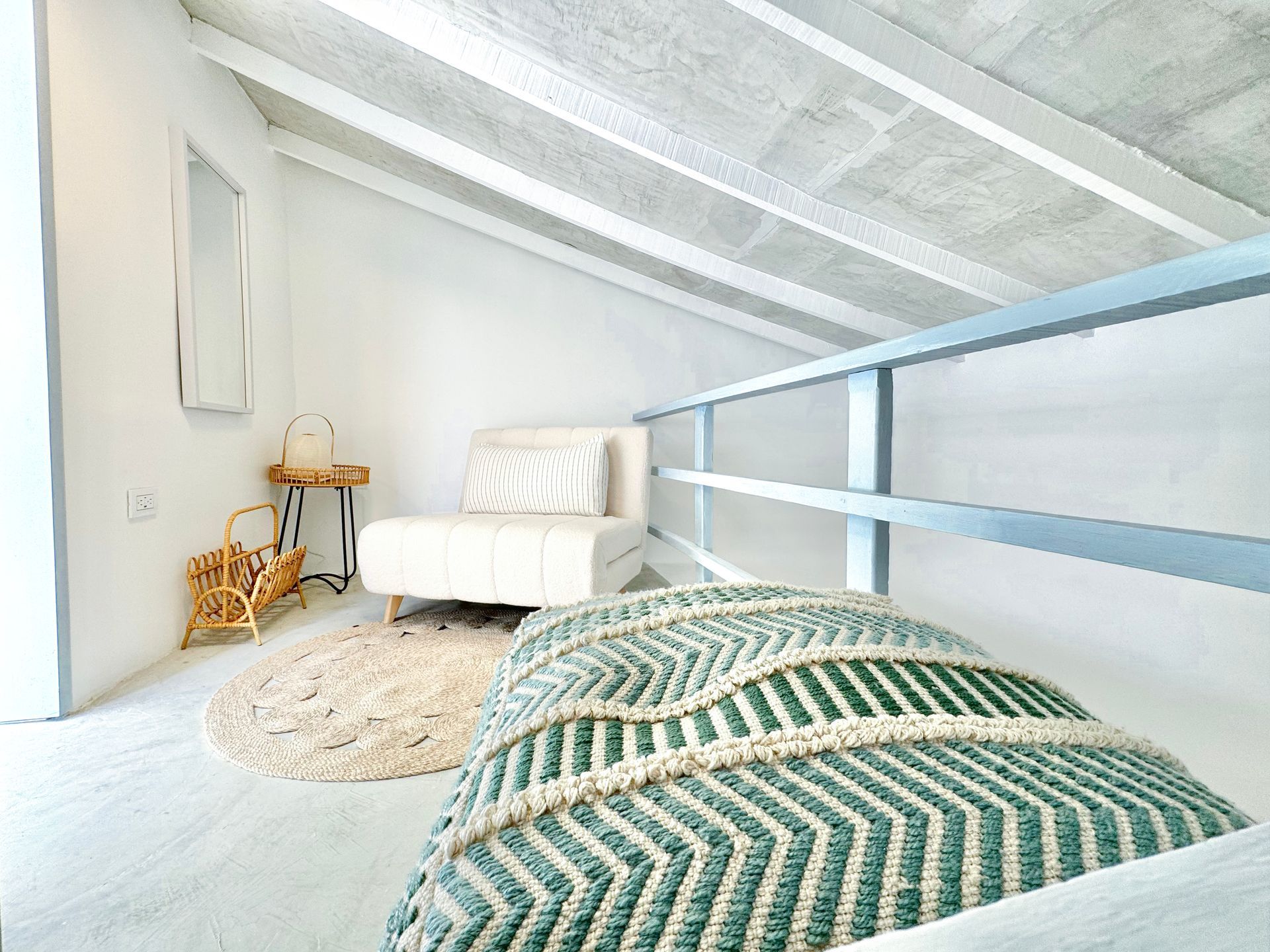 Habitación moderna con cama doble, ropa de cama a rayas verdes y blancas, y un loft accesible por escaleras azules.