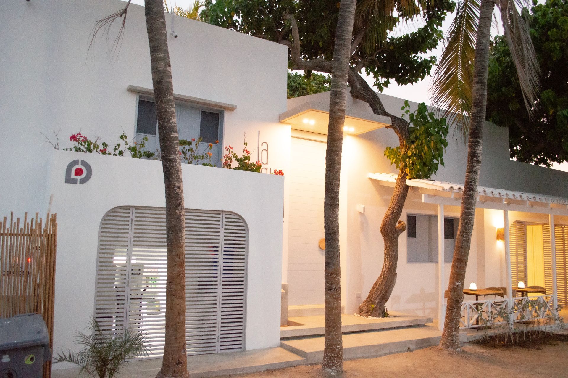 Fachada del Hotel Laguna by LD Hoteles en Los Roques, con balcón adornado con flores y palmeras al frente.