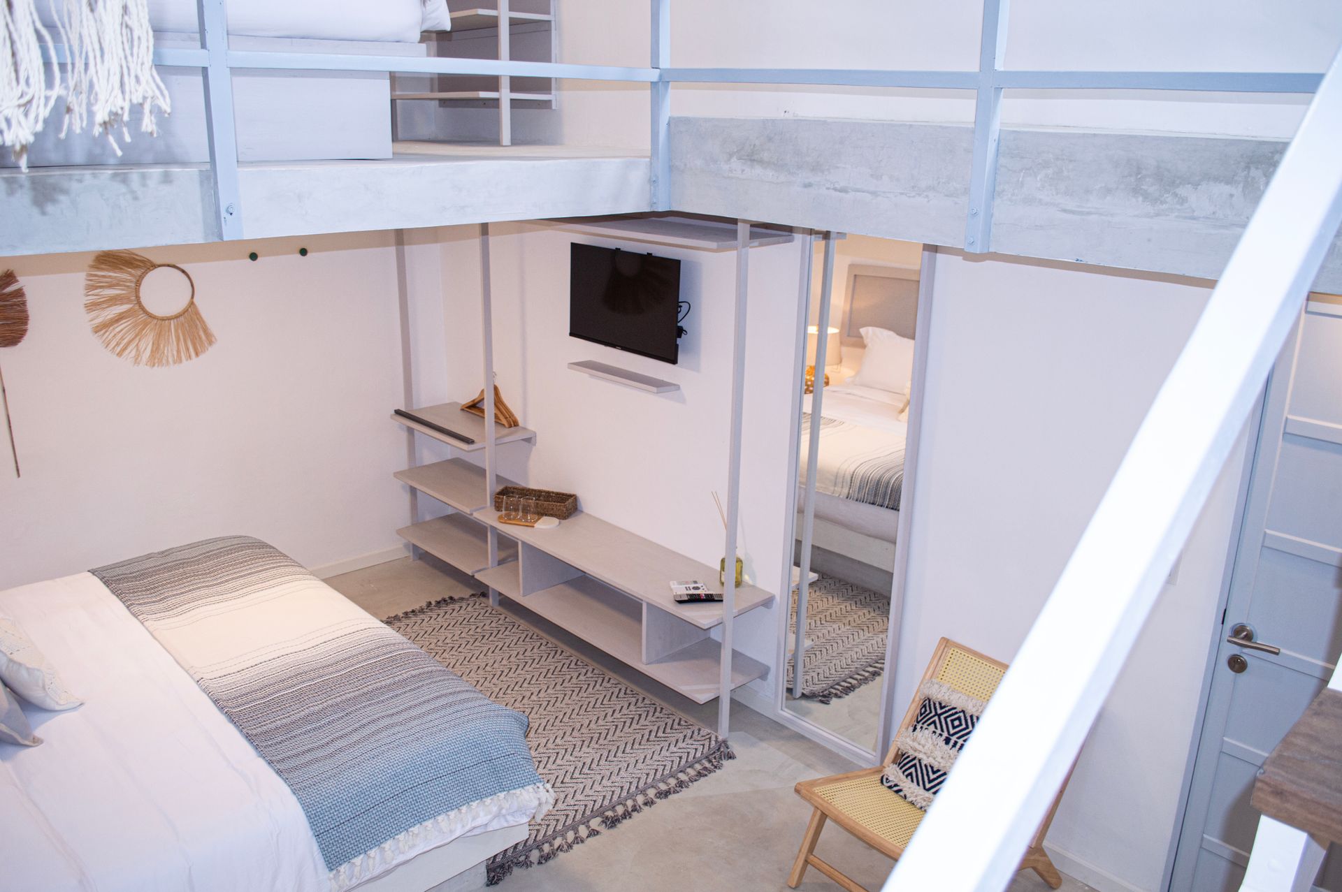 Habitación con cama grande, ropa de cama blanca y estampada, y ventana con persianas cerradas.