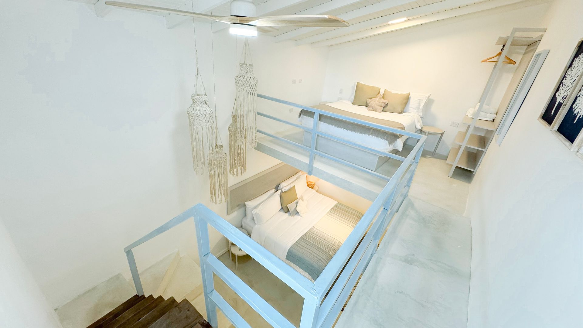 Habitación moderna y luminosa con cama doble, loft accesible por escaleras y decoración minimalista.