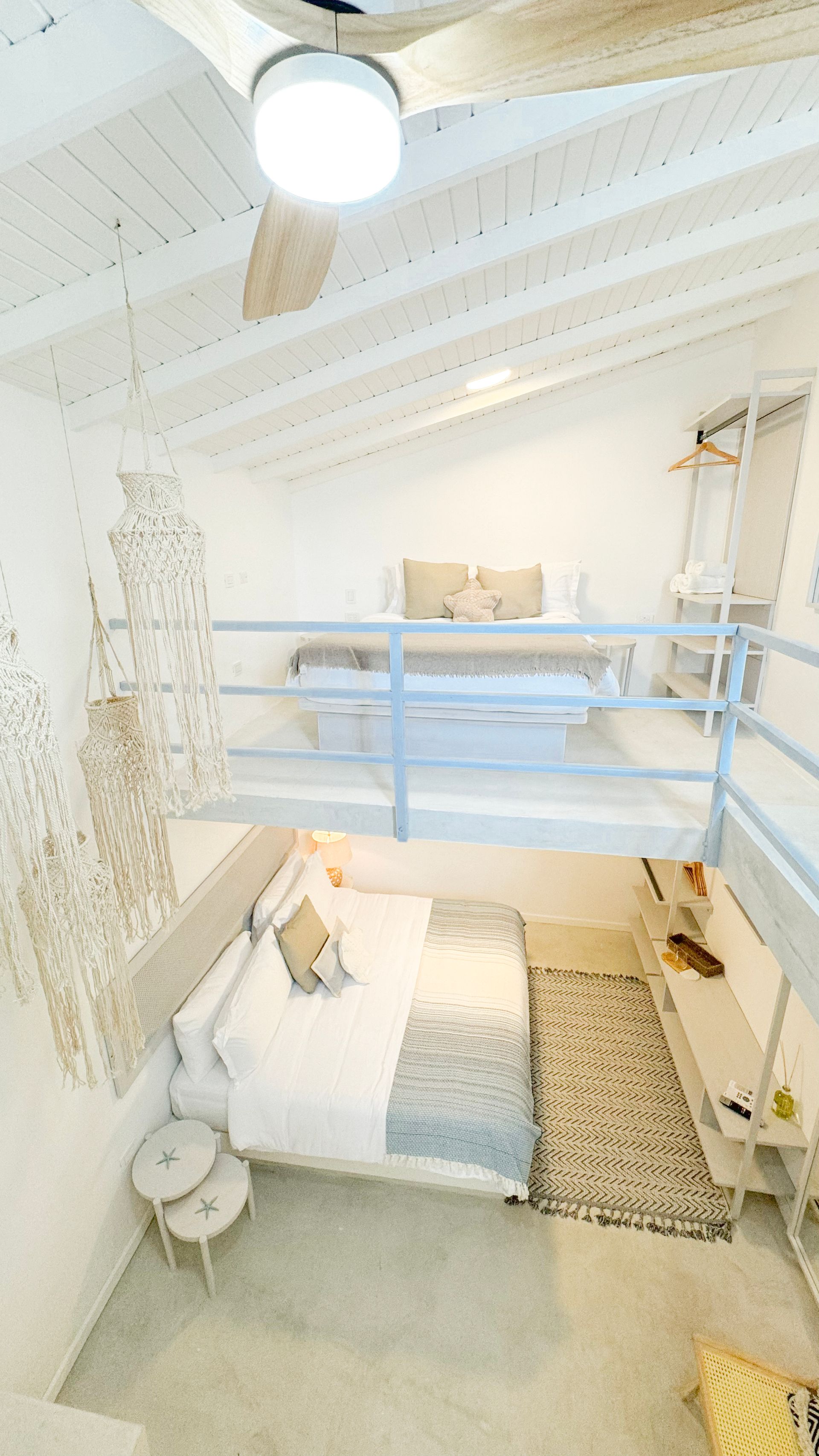 Habitación moderna y luminosa con cama doble, loft accesible por escaleras y decoración minimalista.