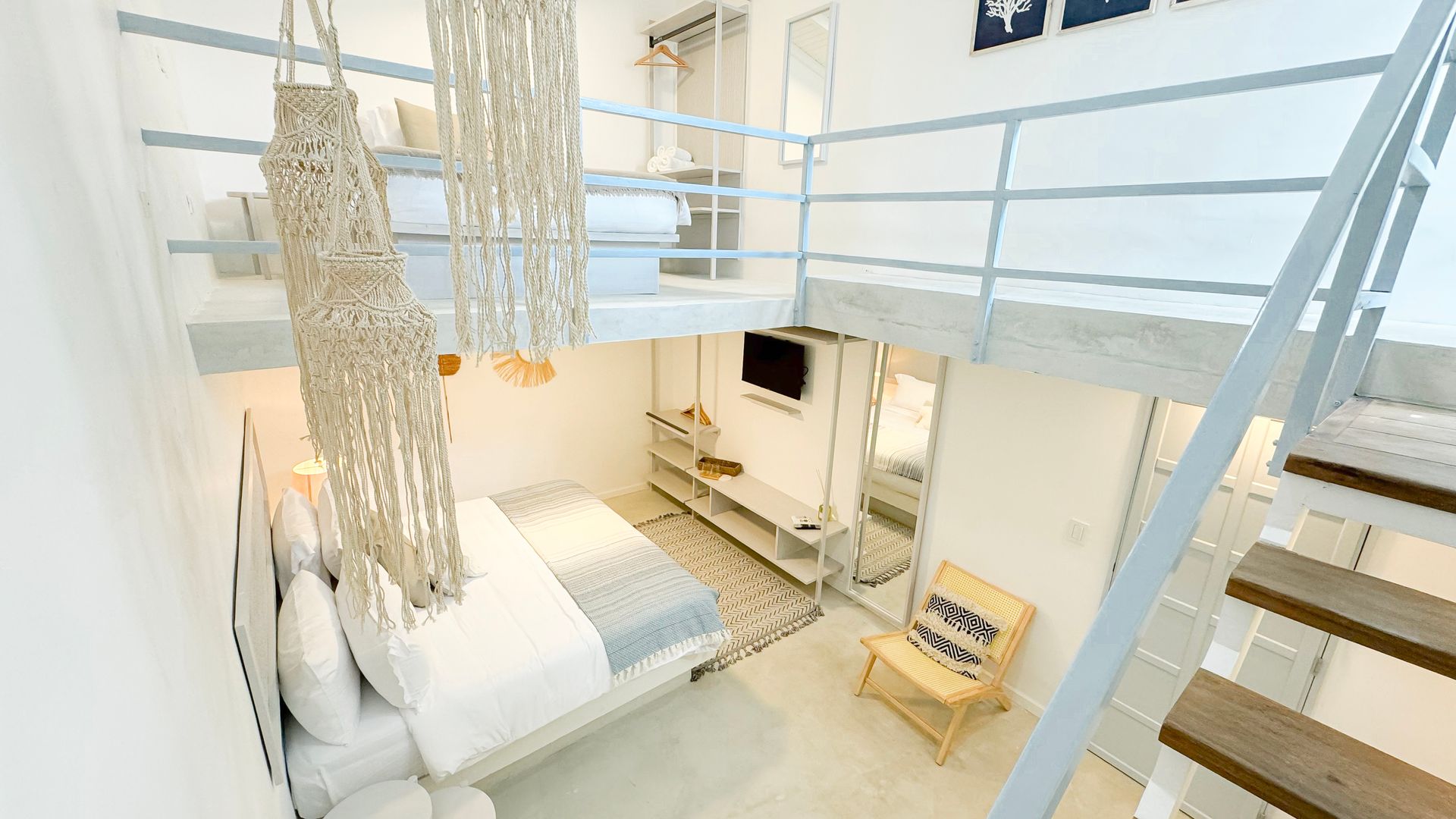 Habitación moderna y luminosa con cama doble, loft accesible por escaleras y decoración minimalista.