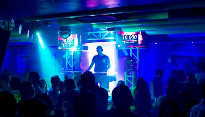 DJ animando la fiesta en 1900 Discoteca, Isla Margarita, con luces coloridas y una multitud emocionada.