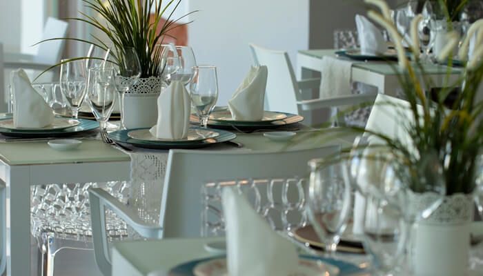 Mesas del Restaurante Aguacero en H2Otel en playa El Agua, con mantelería blanca y decoración elegante.