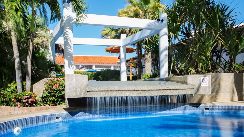 Piscina del Hotel LD Palm Beach en Playa El Agua, con cascada y ambiente tropical.