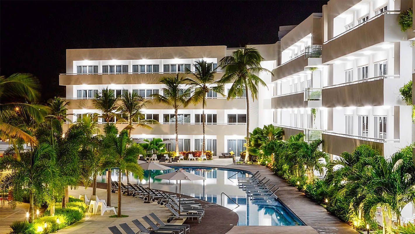 Piscina en LD Plus, Playa El Agua, con tumbonas y palmeras alrededor.