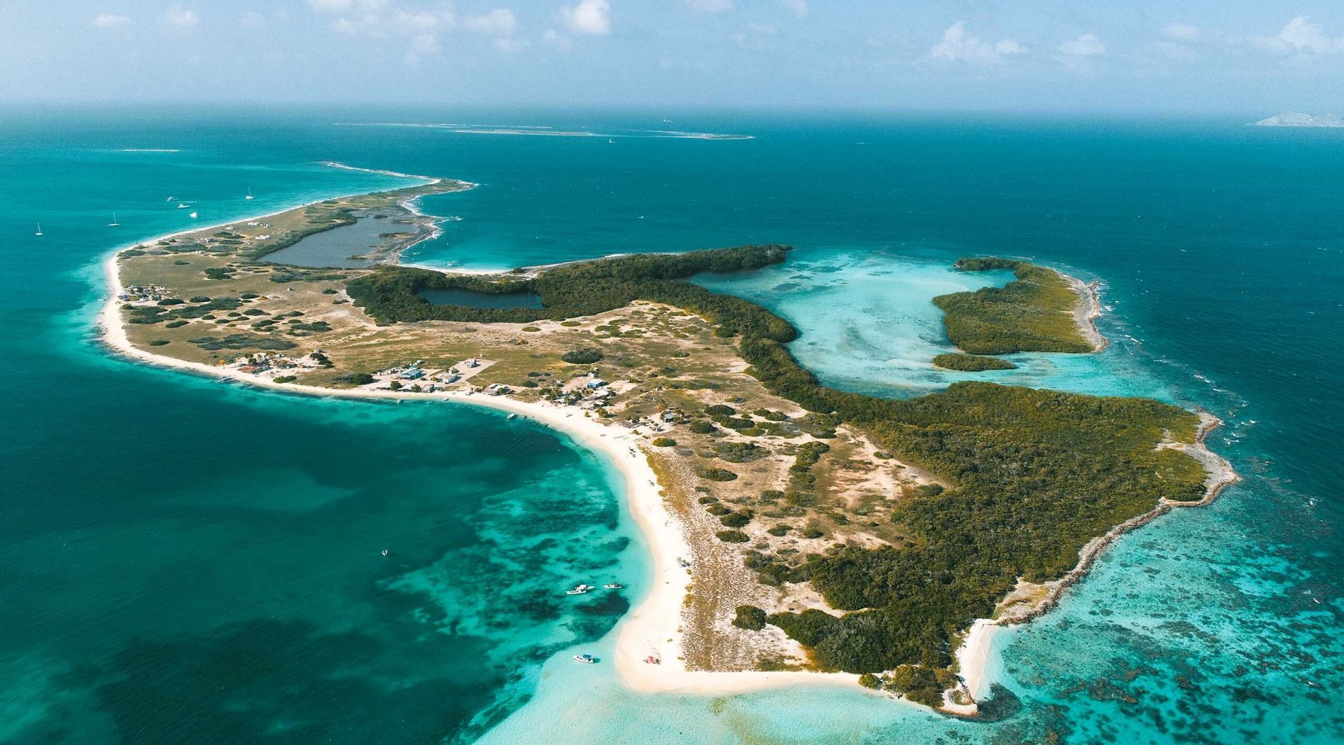 Vista aérea de Crasqui, con aguas turquesas, vegetación y playas de arena, ideal para el turismo.