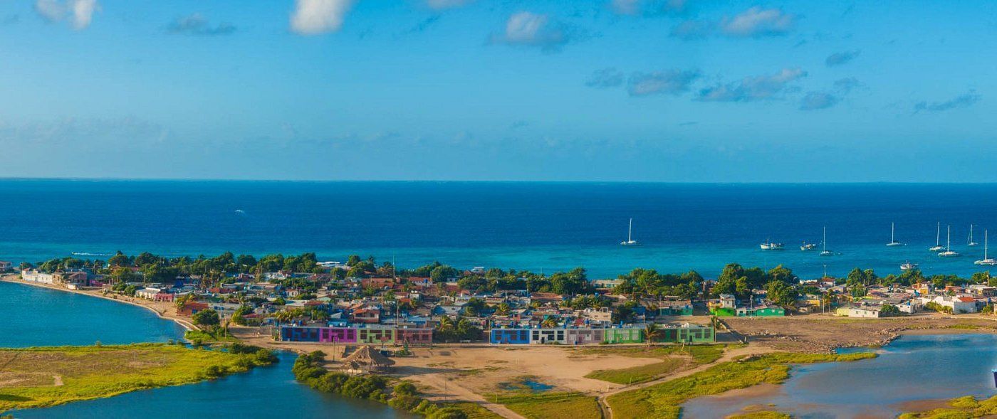 Vista aérea de El Gran Roque, mostrando la comunidad costera, la playa y los barcos en el agua. Ideal para turismo.