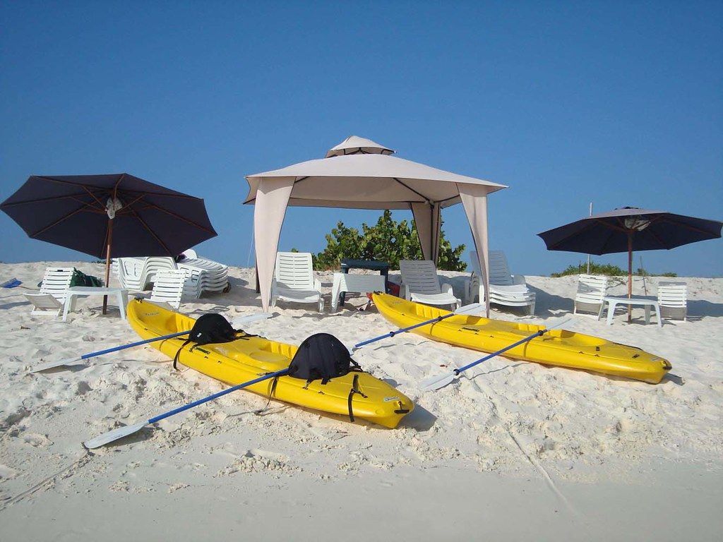 Kayak en Los Roques, disfrutando de actividades acuáticas en una playa soleada con instalaciones recreativas.