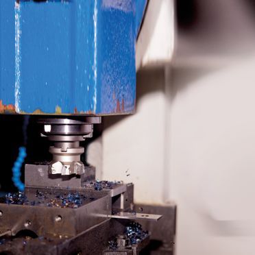 A blue machine is cutting a piece of metal