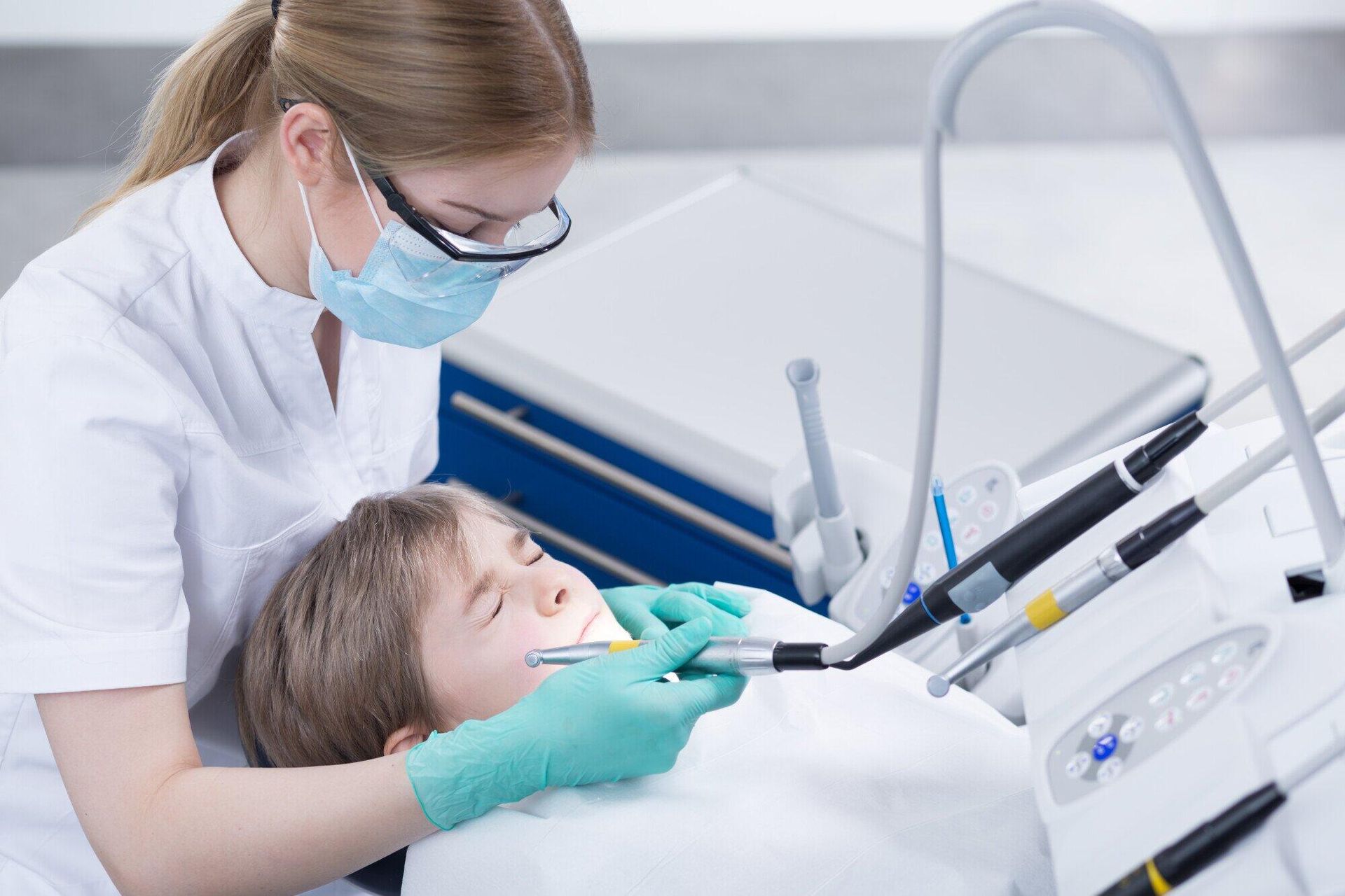 A female dentist is examining a young boy 's teeth in a dental office.