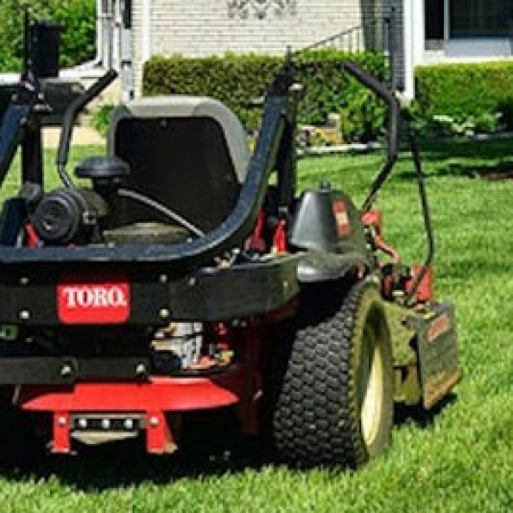 Lawn Mower is Parked in the Grass in Front of a House