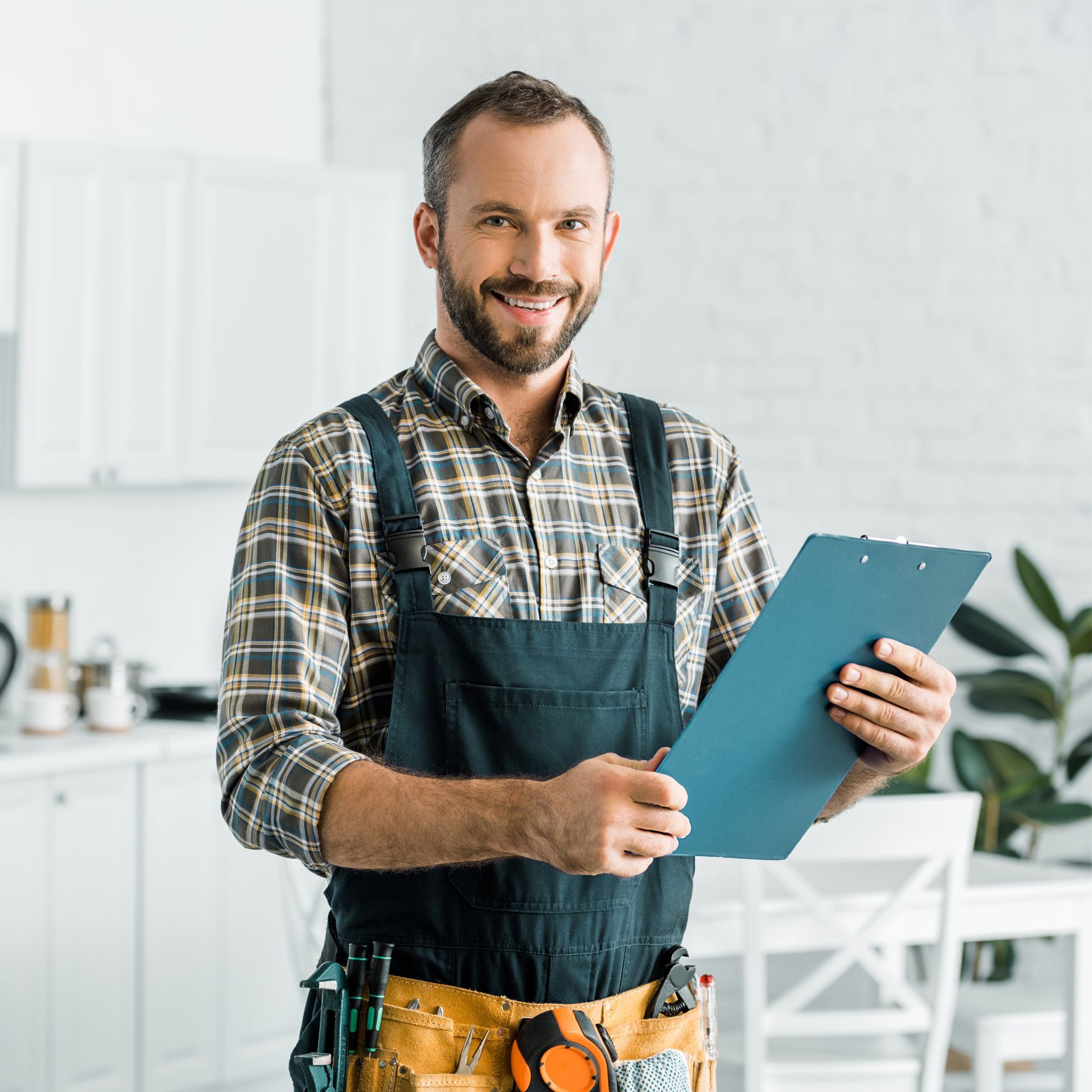 A Man in Overalls is Holding a Clipboard in a Kitchen