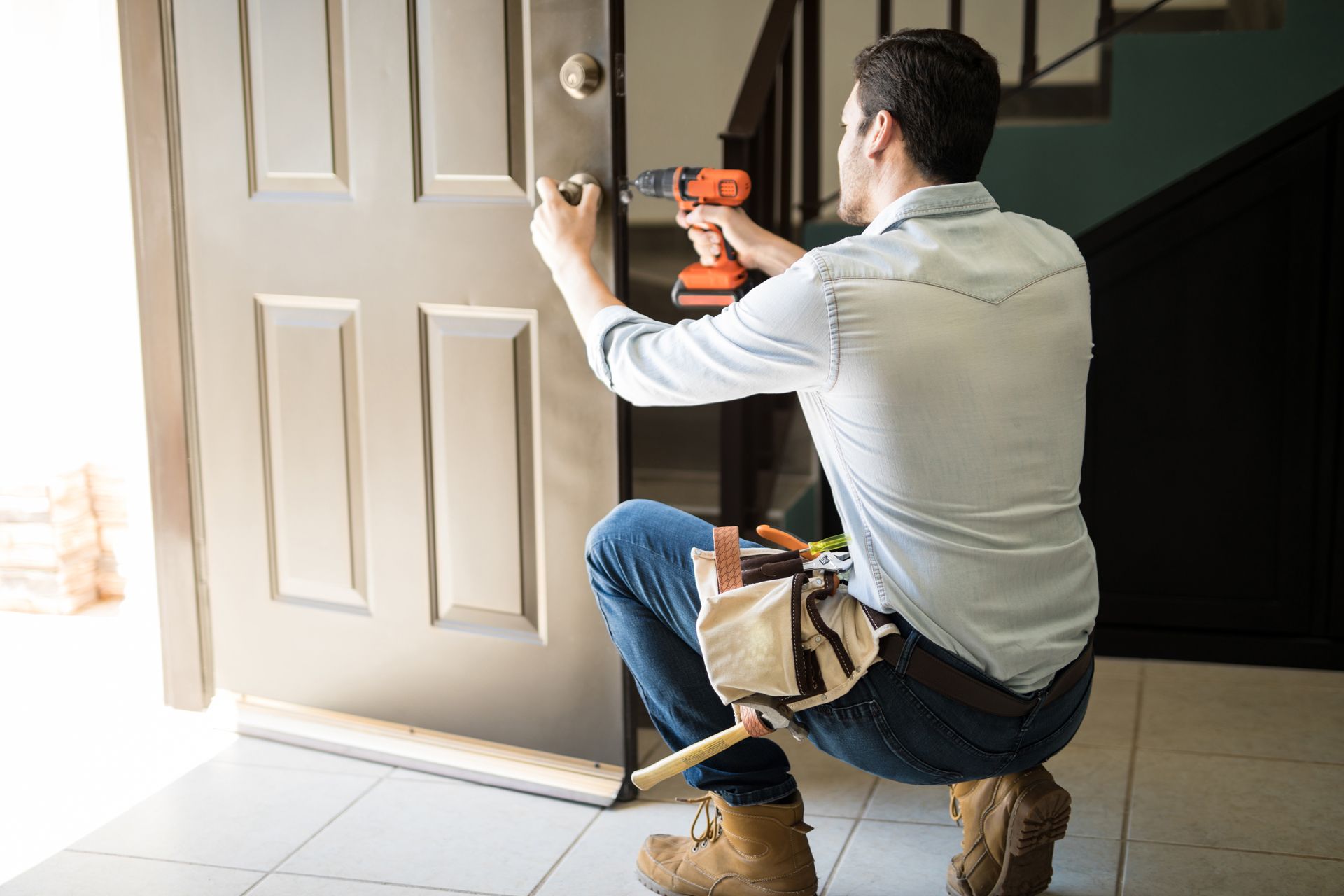 A Man is Fixing a Door With a Drill