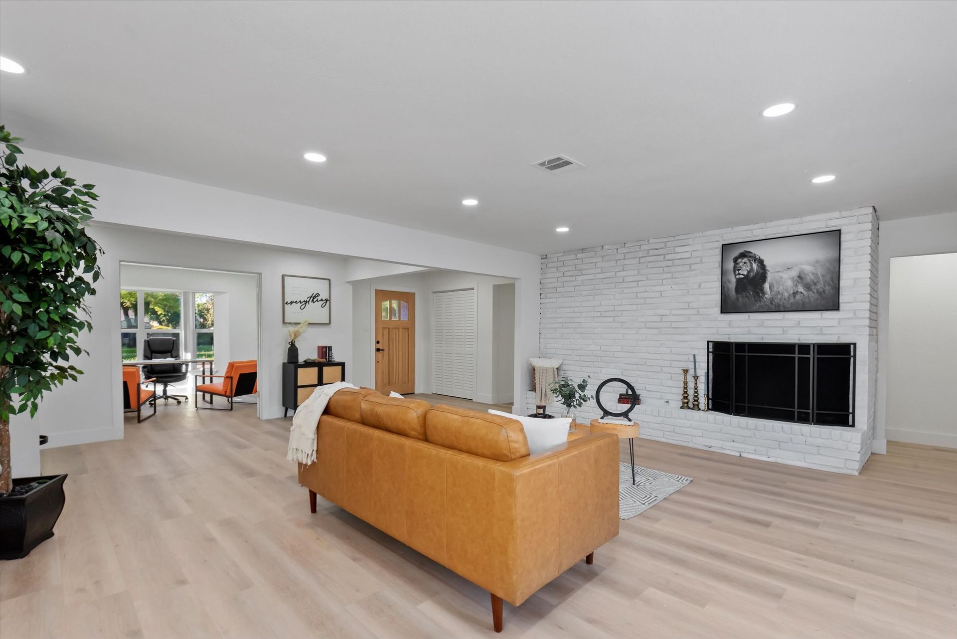 A renovated living room with a brown couch and a fireplace.