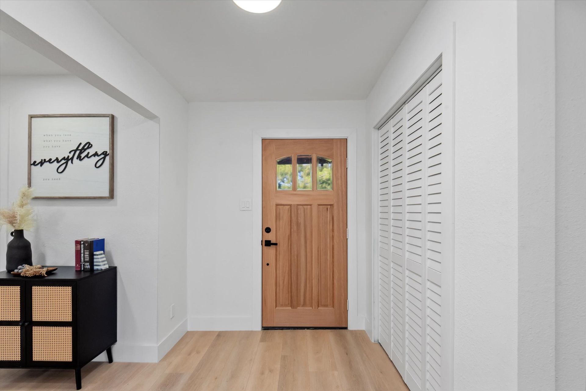A hallway with a wooden door and white shutters.