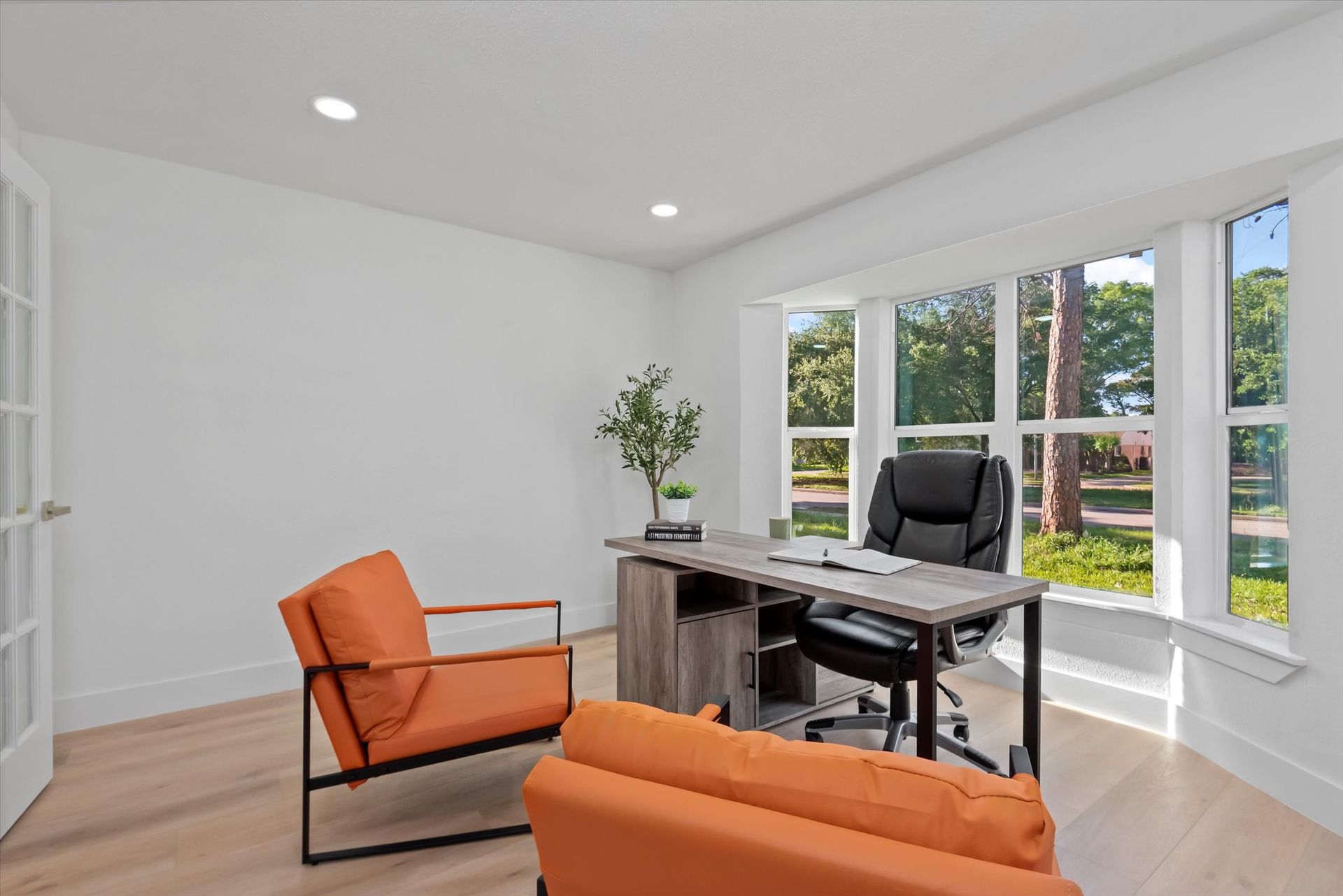 A home office with a desk , chairs , and a couch.