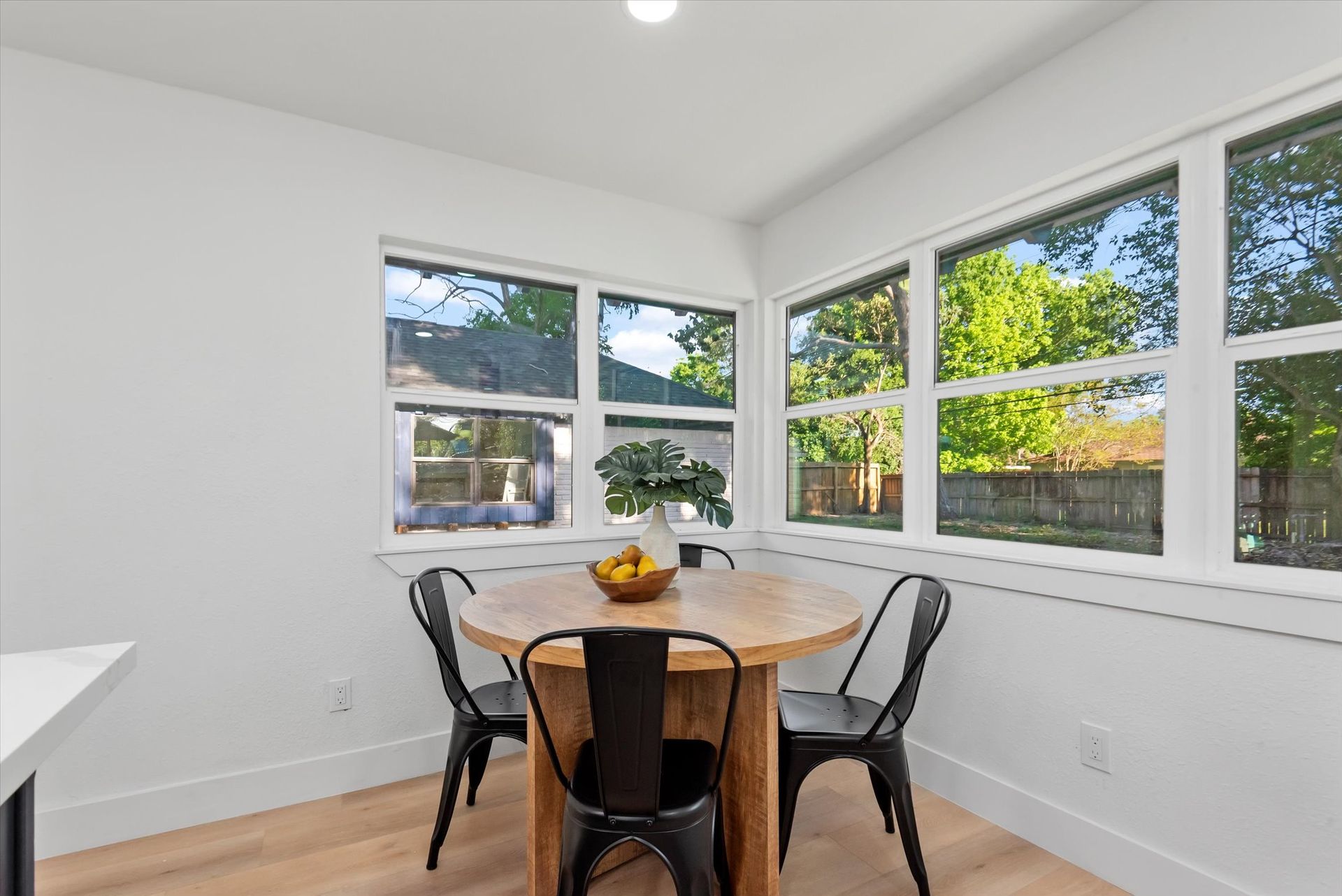 A dining room with a table and chairs and lots of windows.