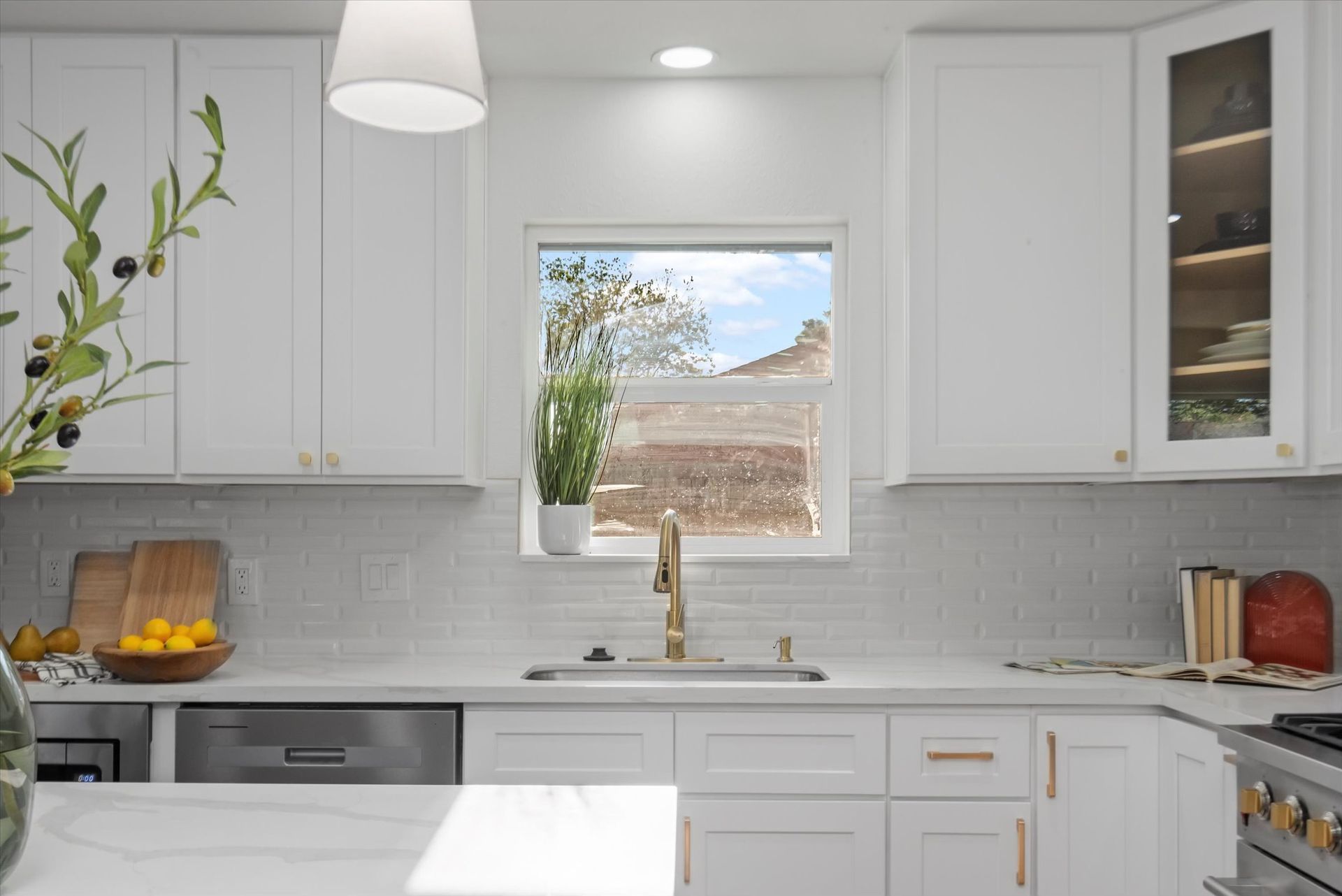 A kitchen with white cabinets , a sink , and a window.