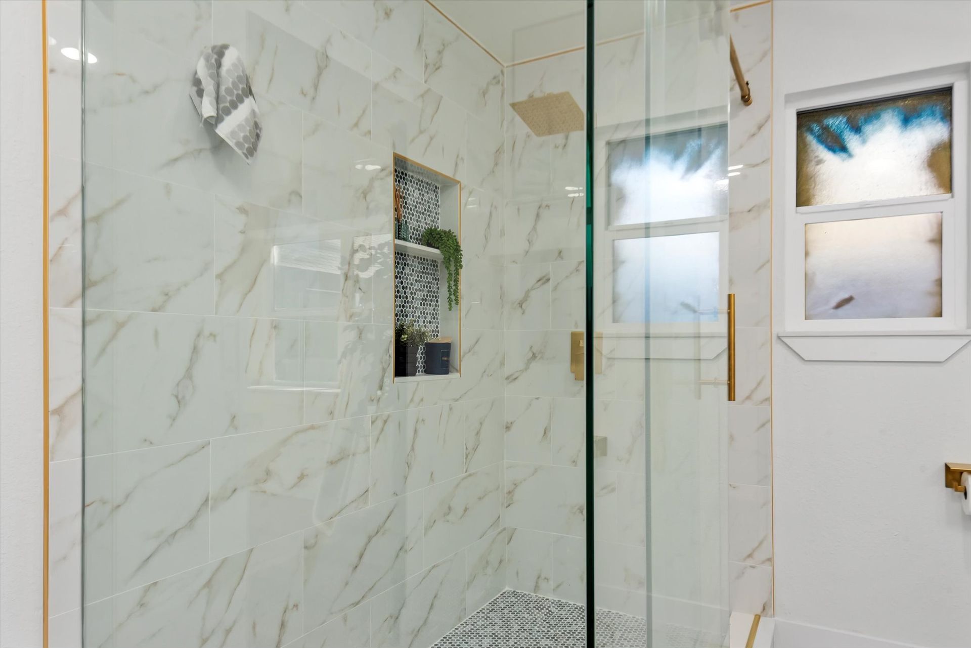 A bathroom with a walk in shower and a window.