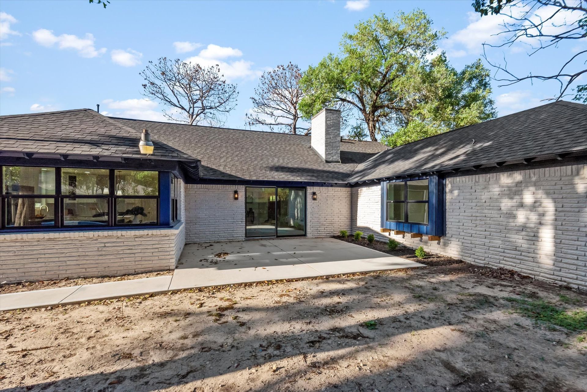 A white brick house with a black roof and blue windows