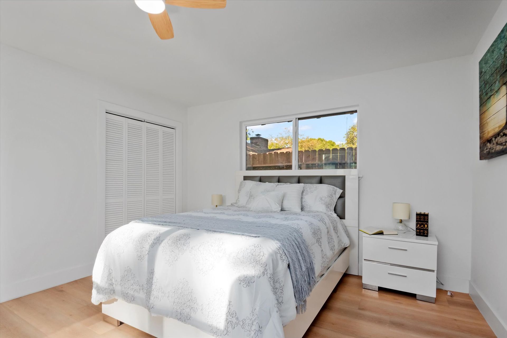 A bedroom with a bed , nightstand , and ceiling fan.