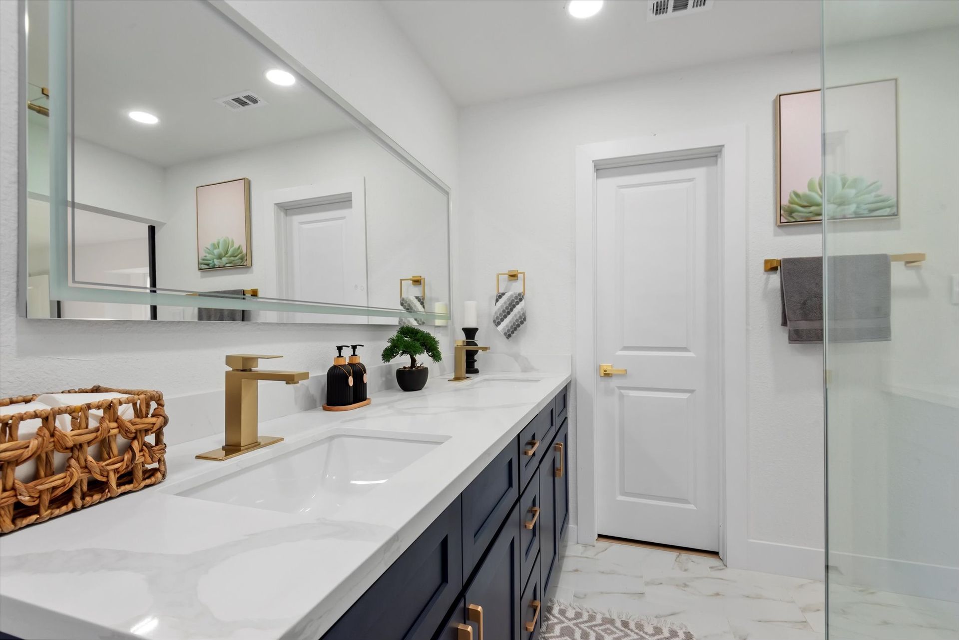A bathroom with two sinks , a large mirror and a walk in shower.