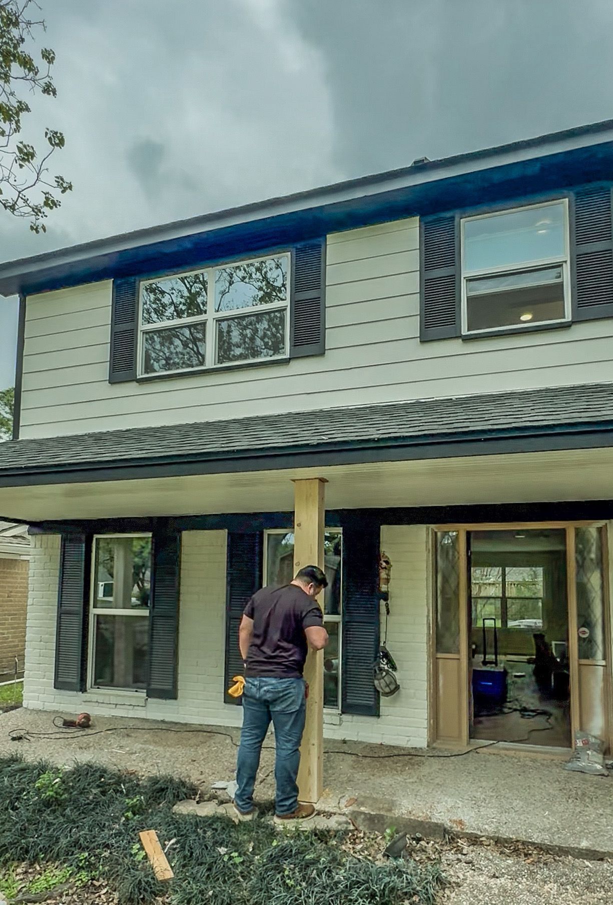 A man is working on a pole in front of a house.
