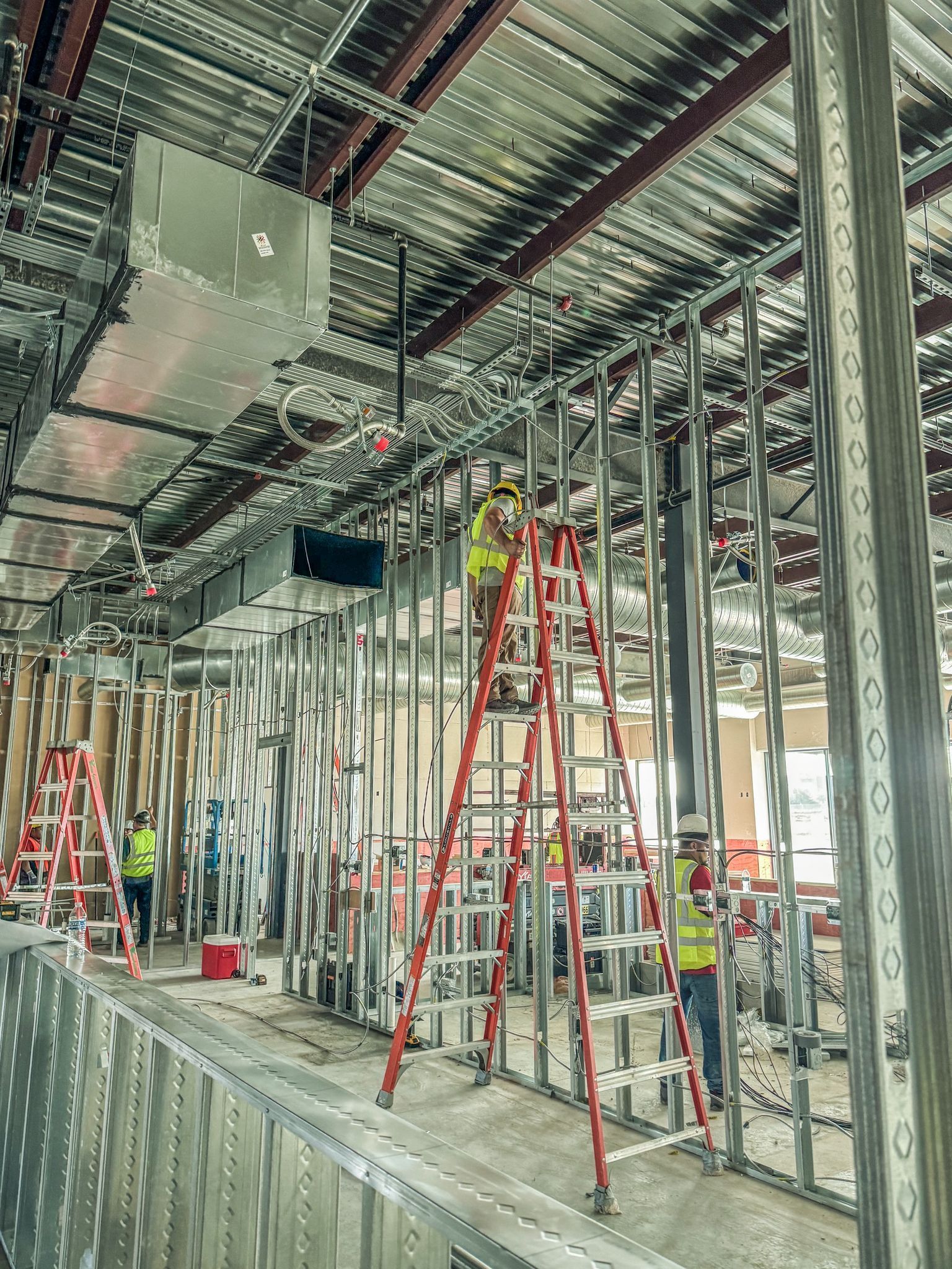 A man is standing on a ladder in a building under construction.