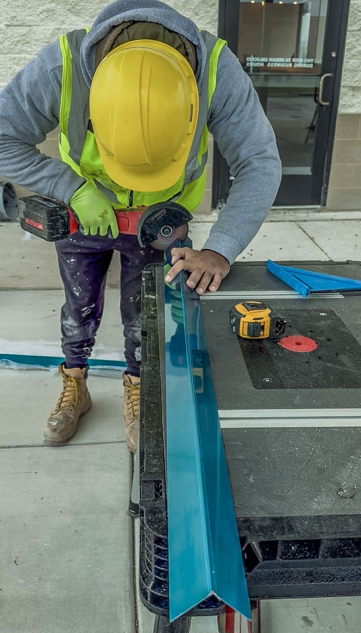 A man wearing a hard hat and safety vest is working on a piece of metal.