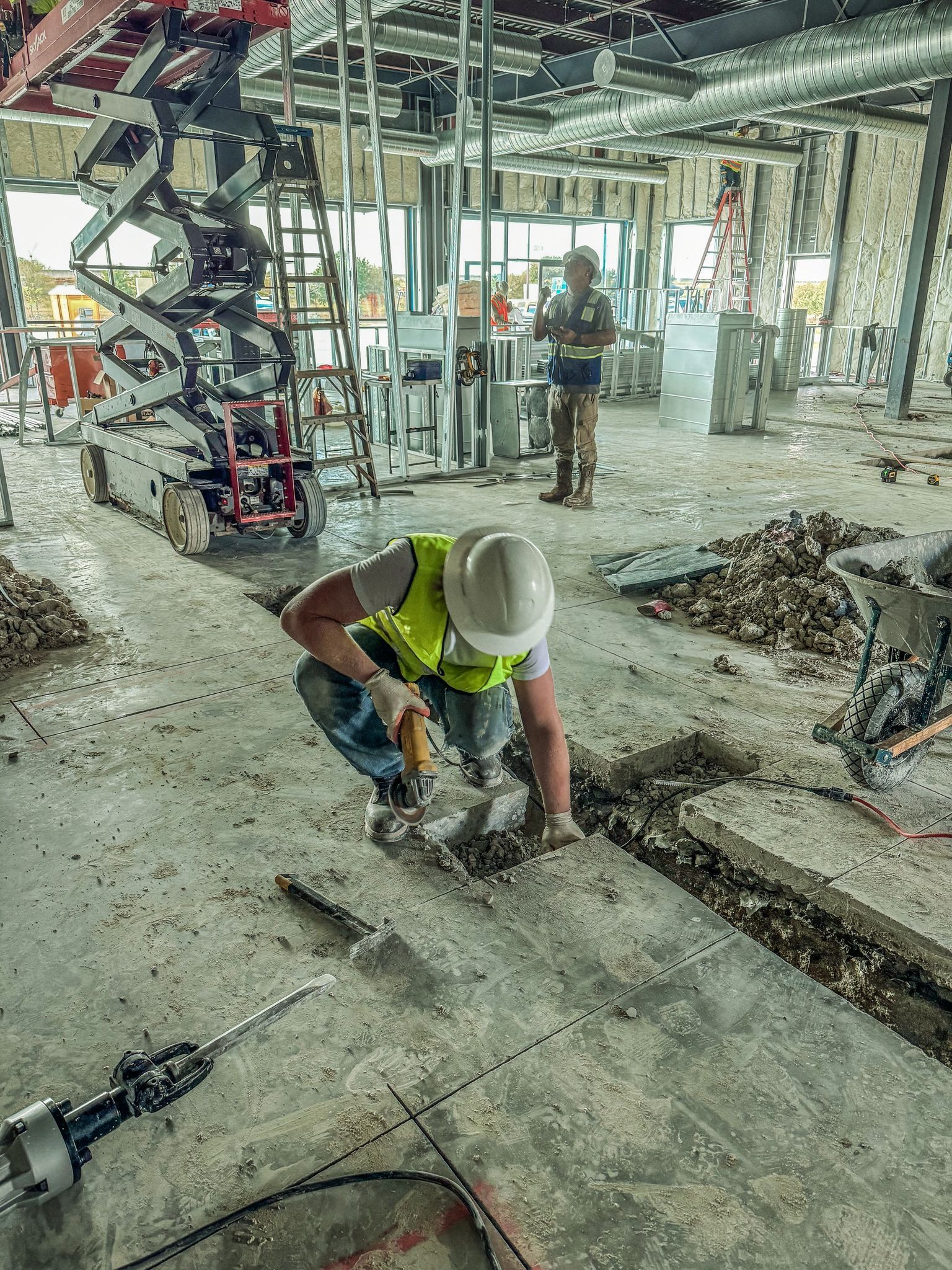 A construction worker is working on the floor of a building under construction.