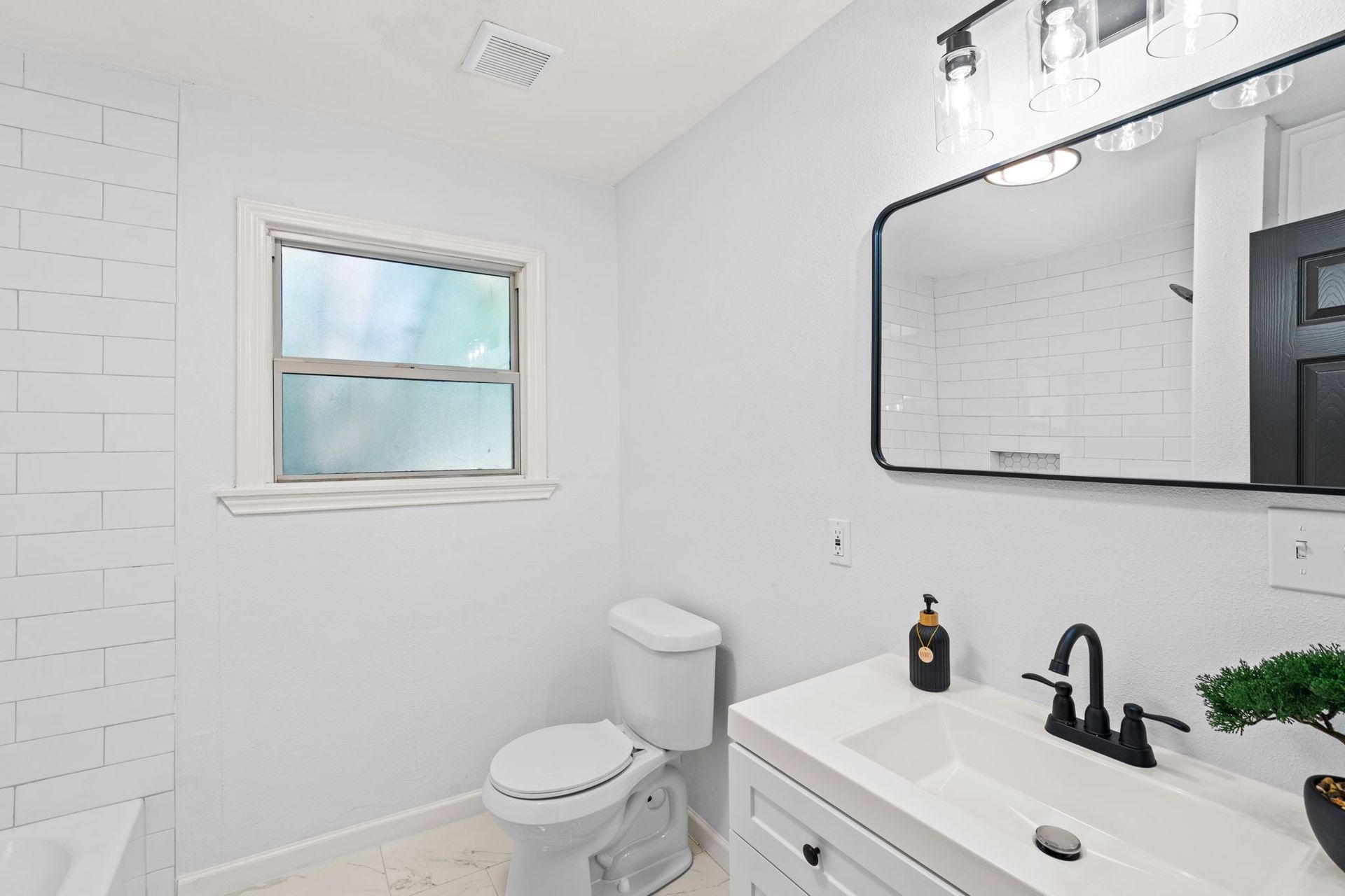 A bathroom with a toilet , sink , and mirror.