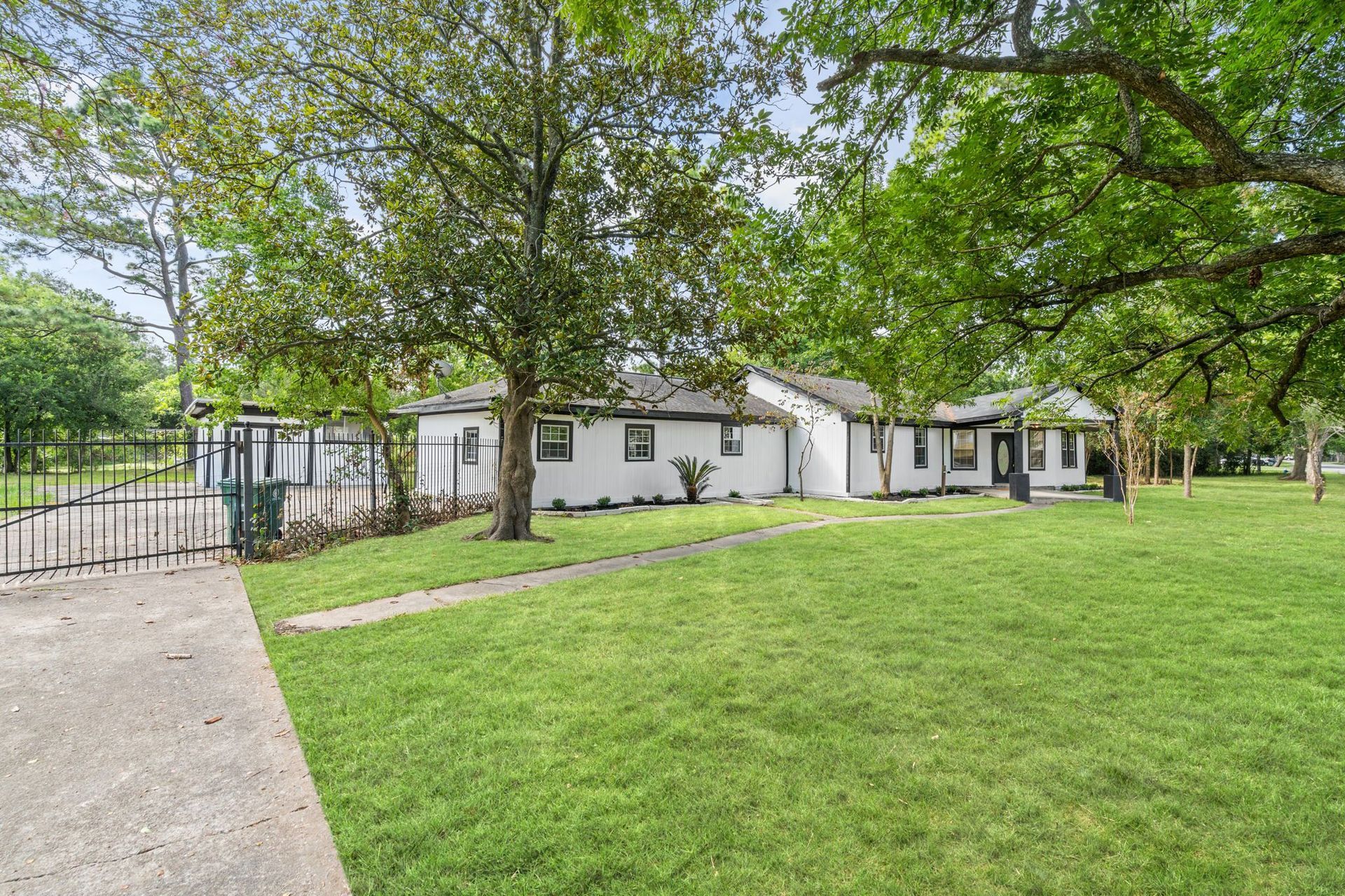 A white house is sitting on top of a lush green field surrounded by trees.