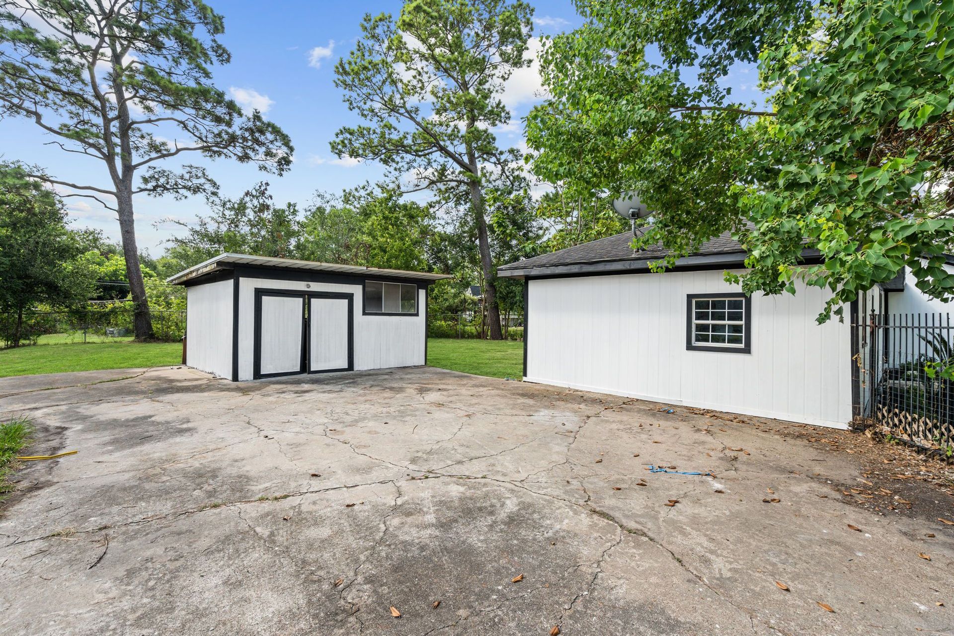 A white house with a garage and a shed in the backyard