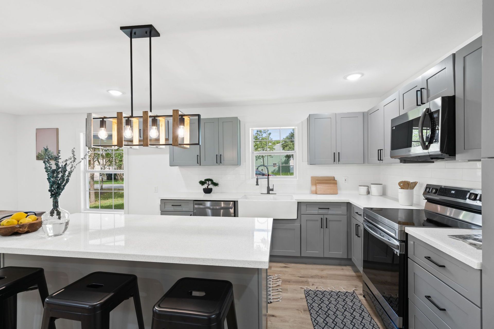 A newly kitchen renovatedwith gray cabinets , white counter tops , stainless steel appliances and a large island.
