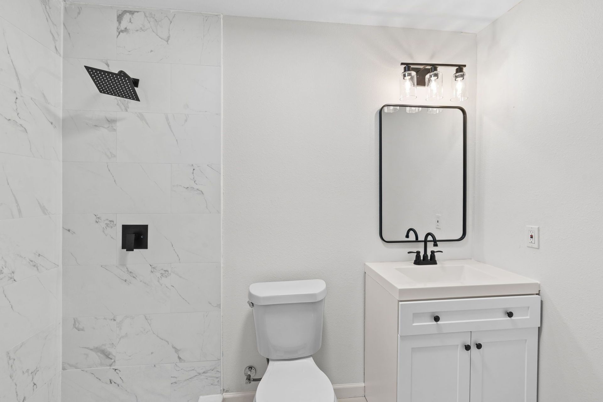 A bathroom with a toilet , sink , mirror and shower.