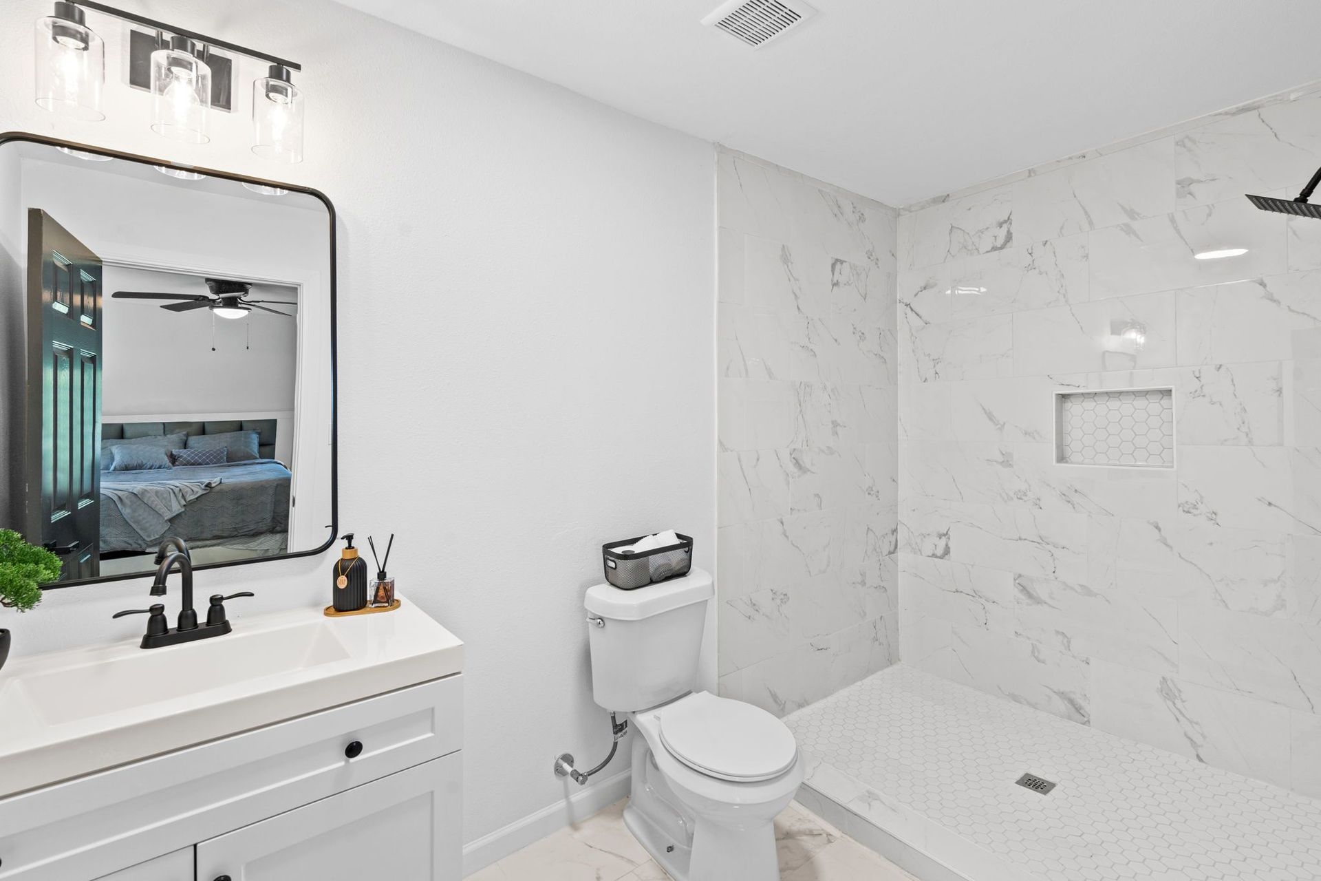 A renovated bathroom with a toilet , sink , mirror and shower.
