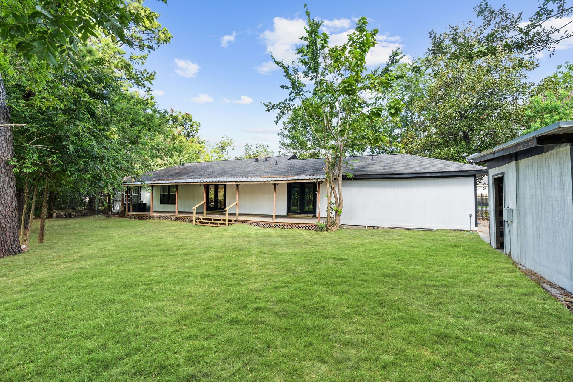 The backyard of a house with a large lawn and a porch.