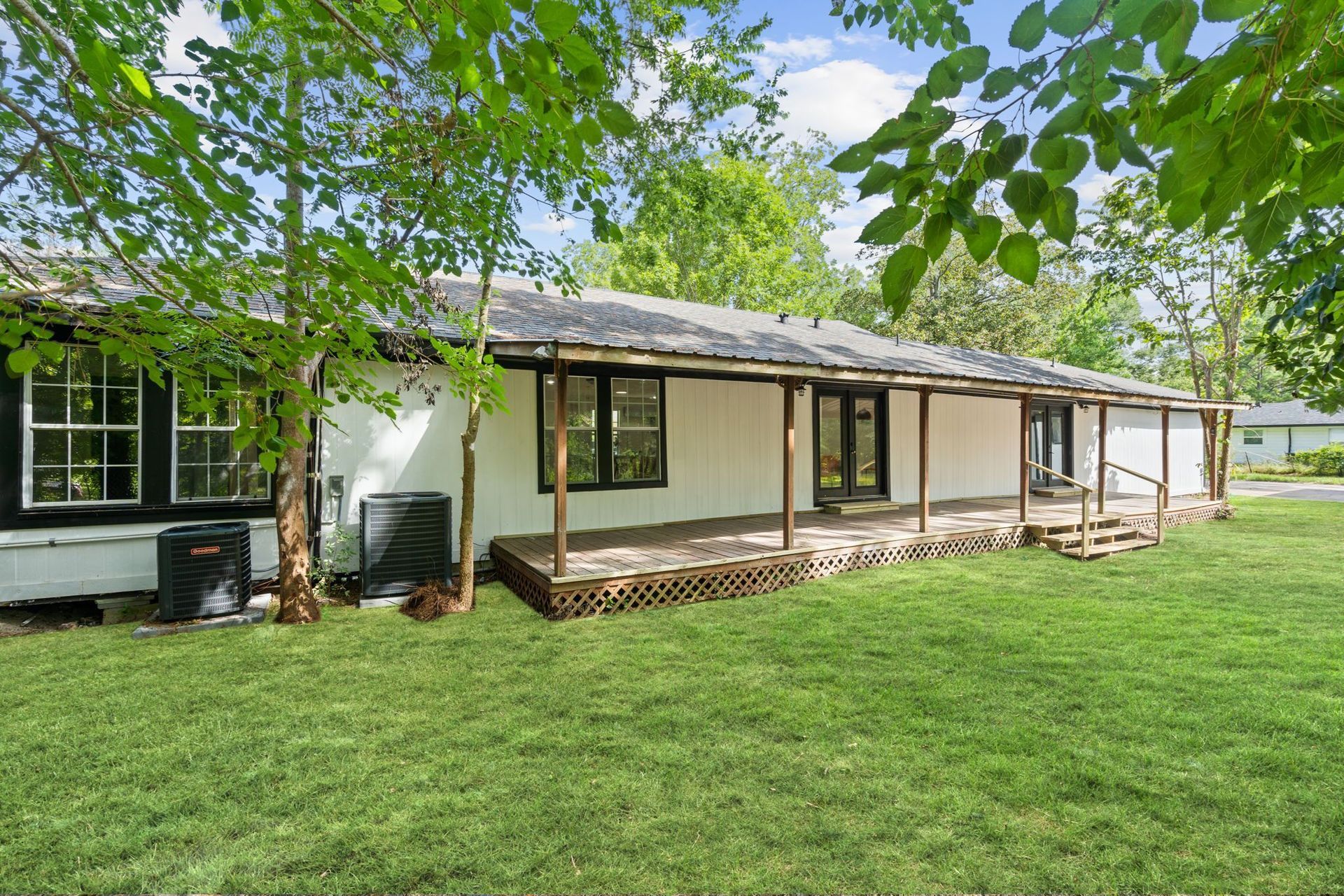 A white house with a porch and a large lawn in front of it.