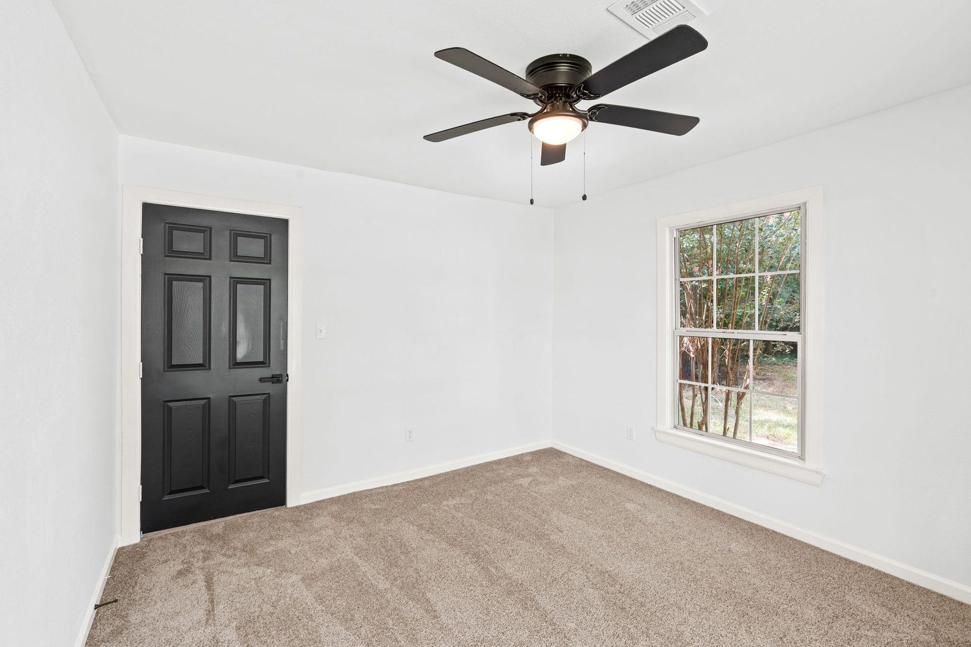An empty bedroom with a ceiling fan and a window.