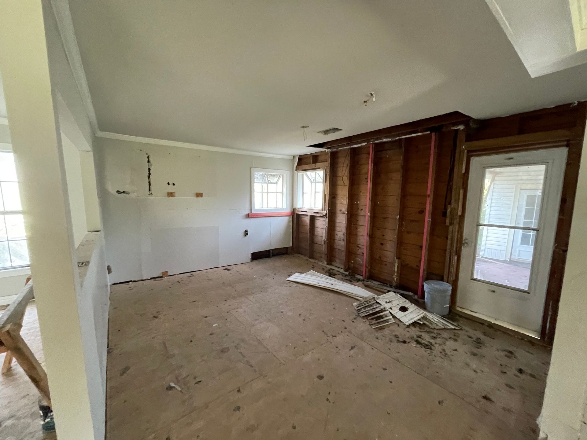 An empty room renovating with a wooden floor and a door.