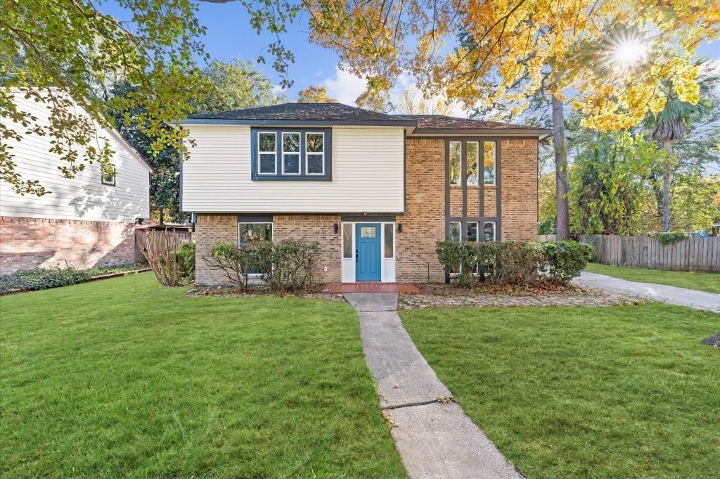 Two-story house with beige and blue facade, walkway to blue front door, and green lawn.