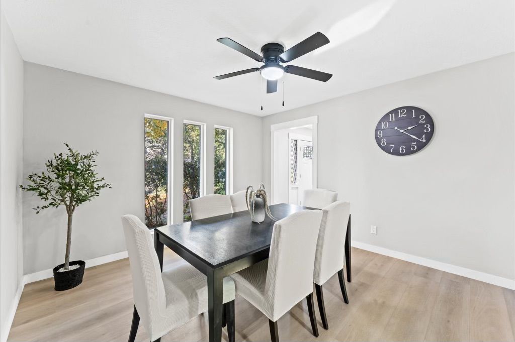 A dining room with a table and chairs and a ceiling fan.