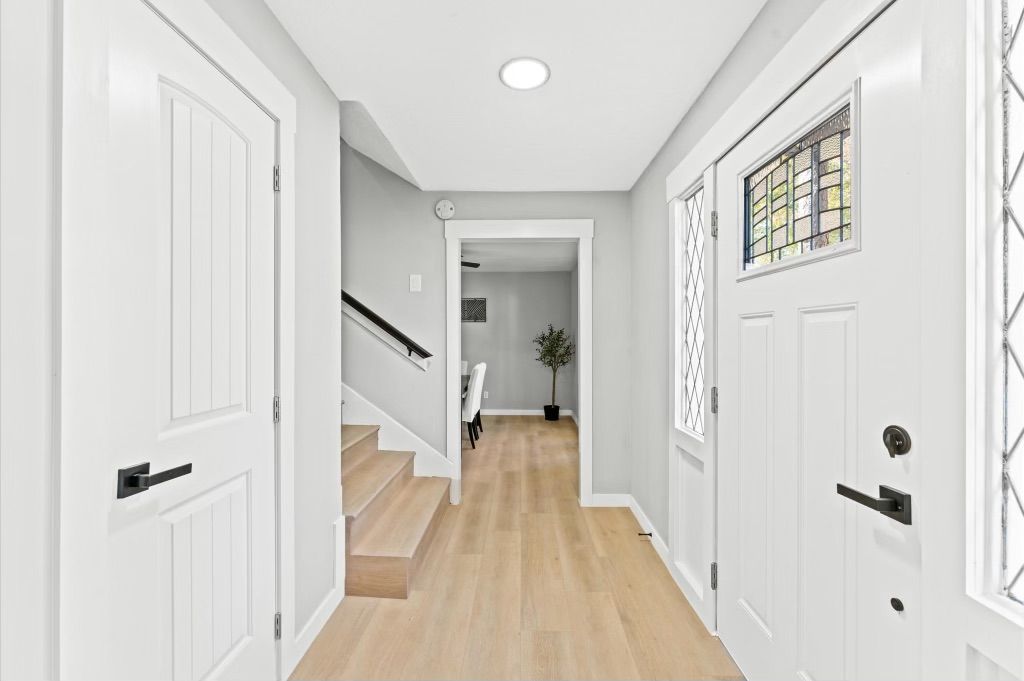 A renovated hallway with white doors and wooden floors leading to a staircase.