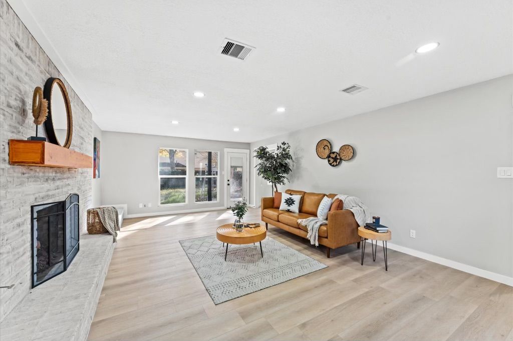 A living room with a couch , coffee table , fireplace and brick wall.