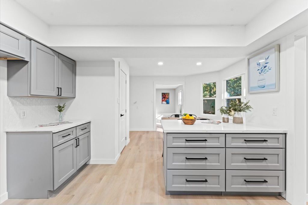 A kitchen with gray cabinets and a large island in the middle.
