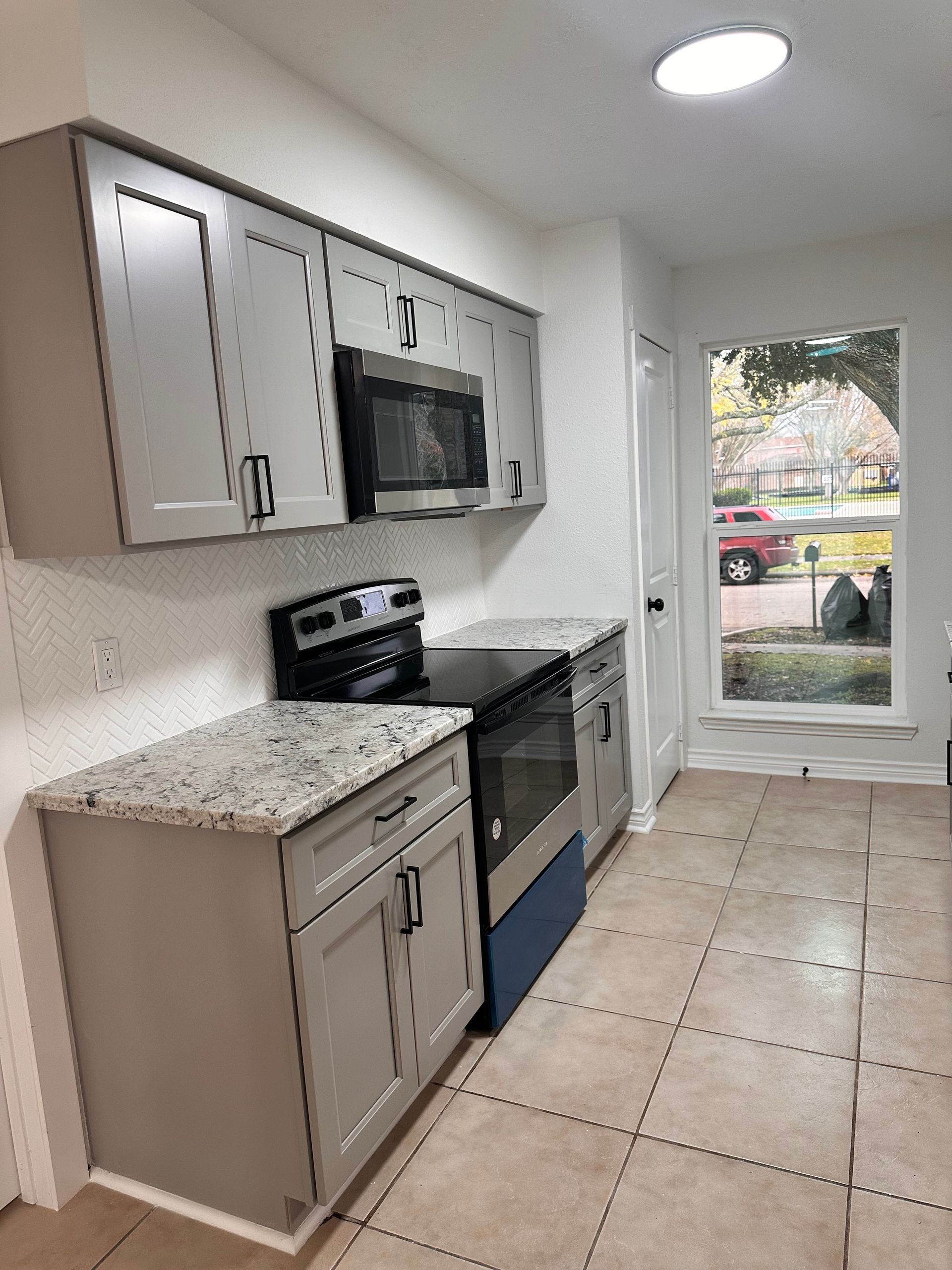 A kitchen with stainless steel appliances and gray cabinets
