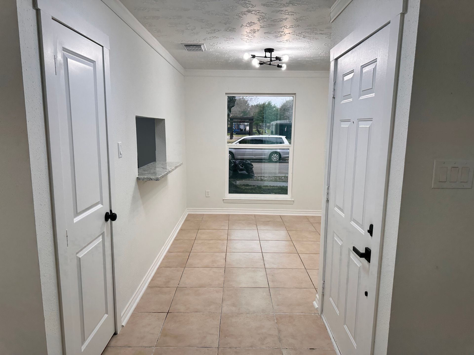 An empty hallway with white doors and a window.
