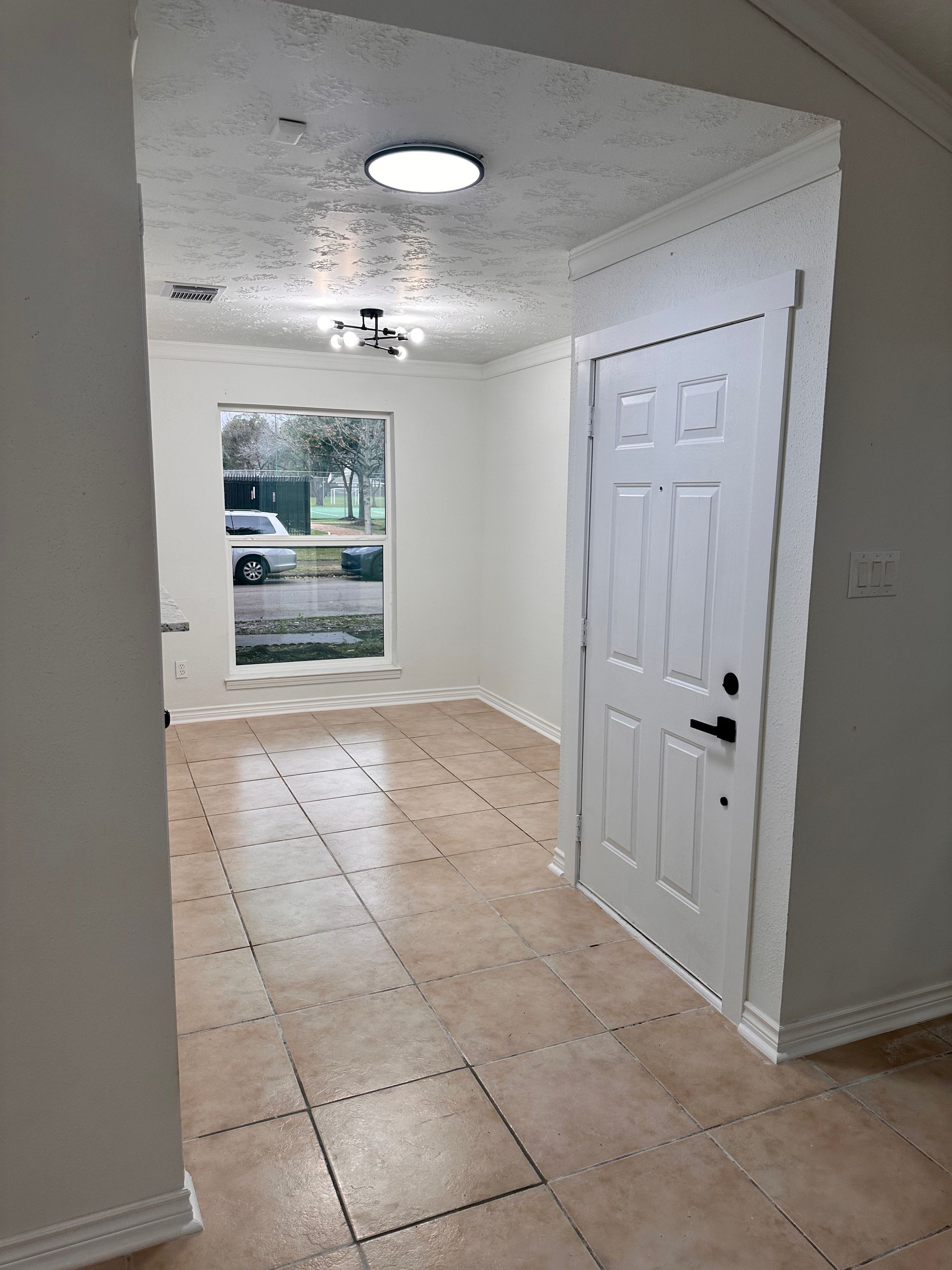 A hallway in a house with a white door and a window.